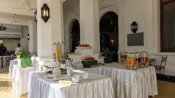 Un buffet de petit-déjeuner avec différents stands de nourriture, notamment un stand de céréales, et un espace repas avec des tables et des chaises.
