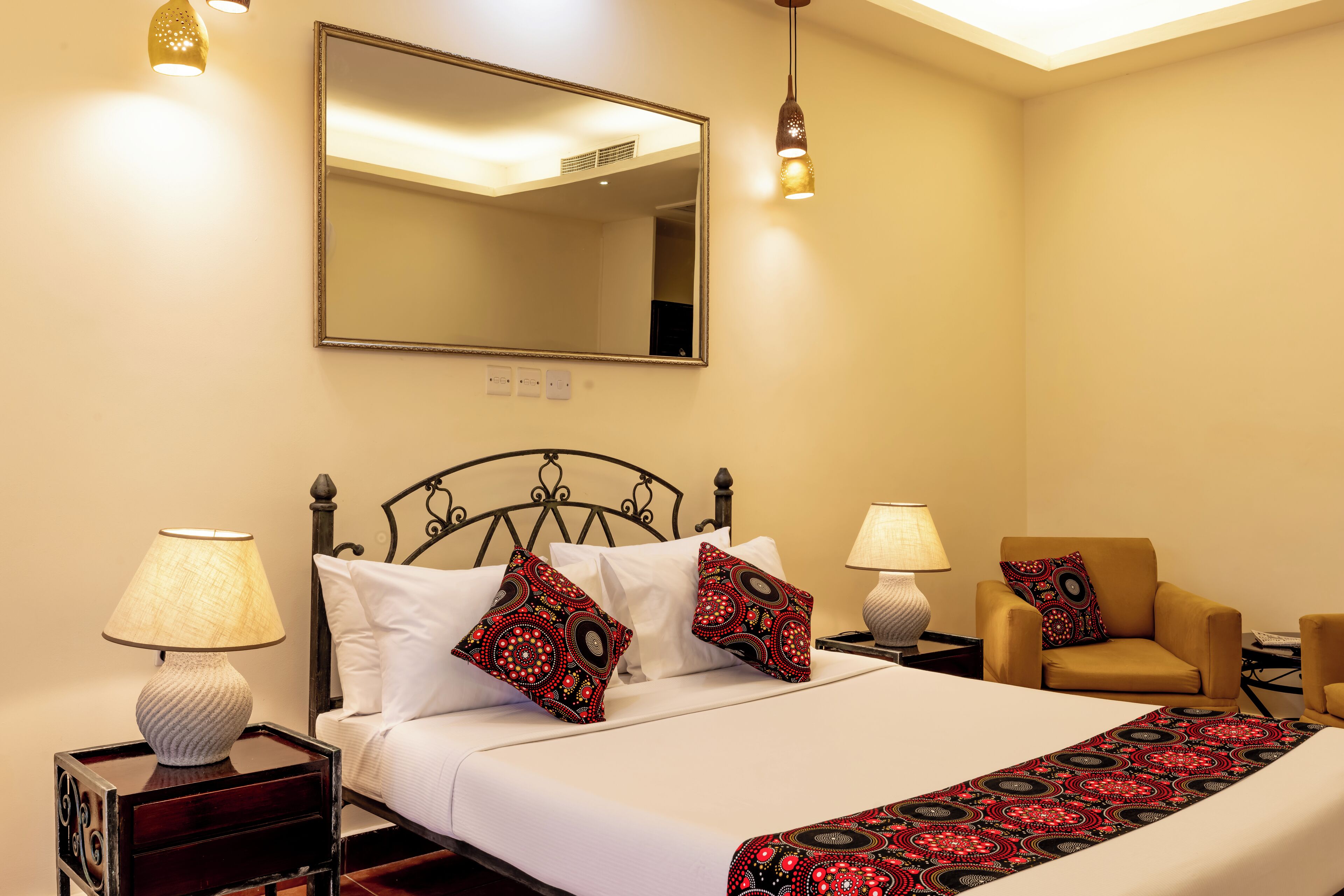 A hotel room with a bed, two nightstands, a chair, a mirror, and two wall-mounted lamps.