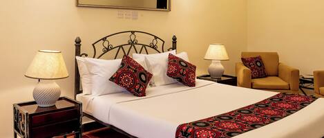 A hotel room with a bed, two nightstands, a chair, a mirror, and two wall-mounted lamps.