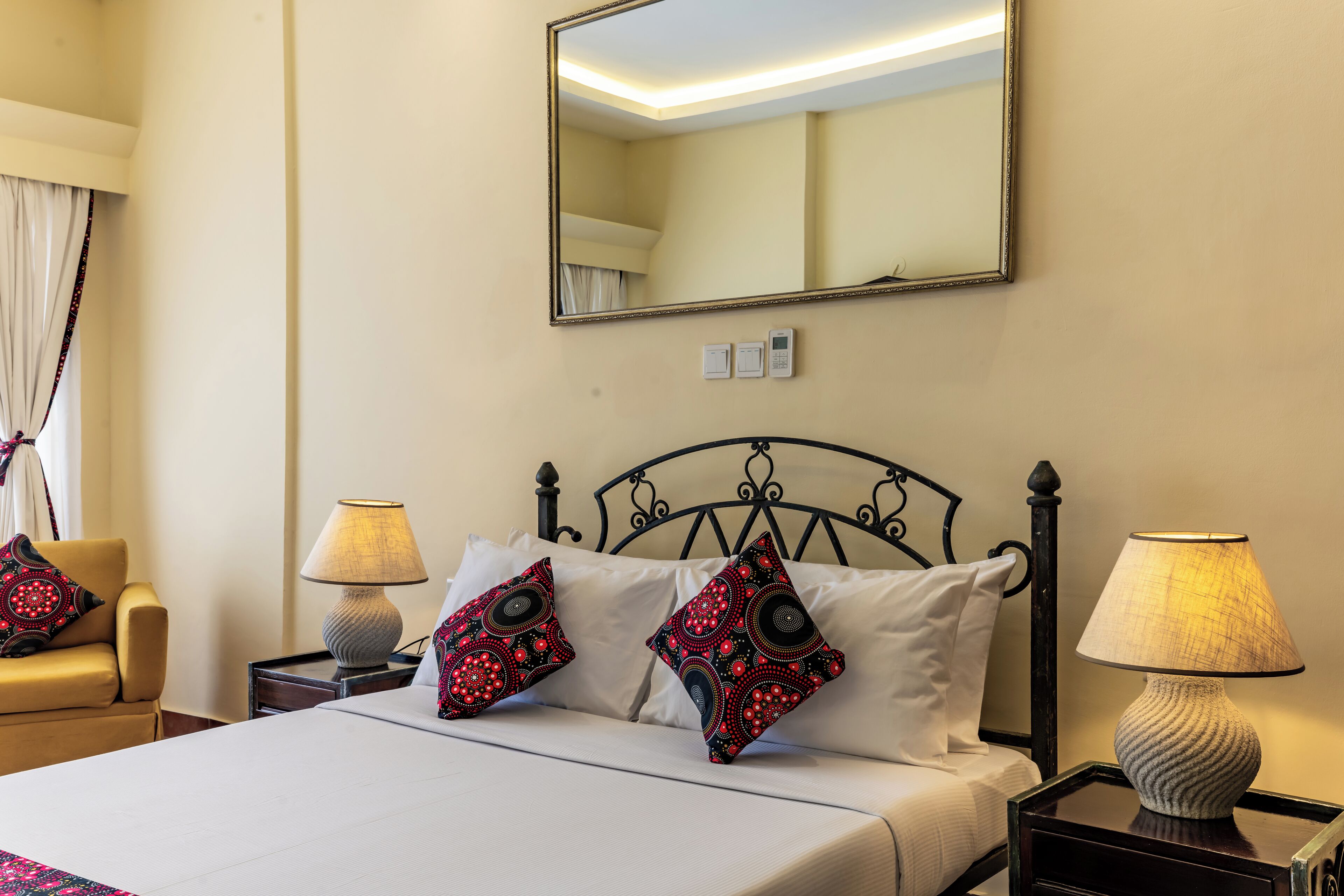 Une chambre d’hôtel avec un lit, deux lampes de chevet, un miroir et une table de chevet.