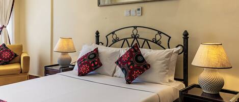 Une chambre d’hôtel avec un lit, deux lampes de chevet, un miroir et une table de chevet.