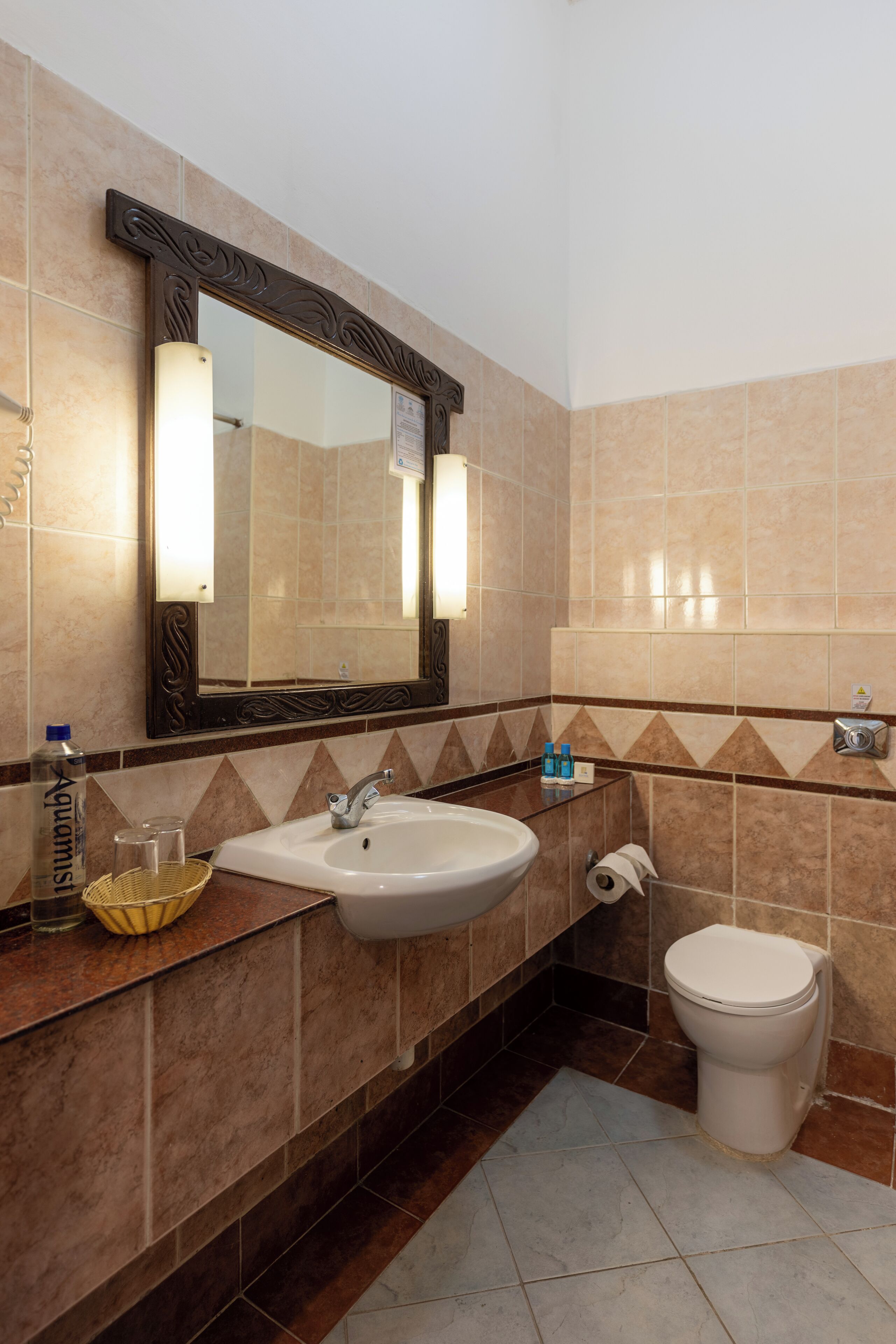 A bathroom with a sink, mirror, toilet, and a towel rack.