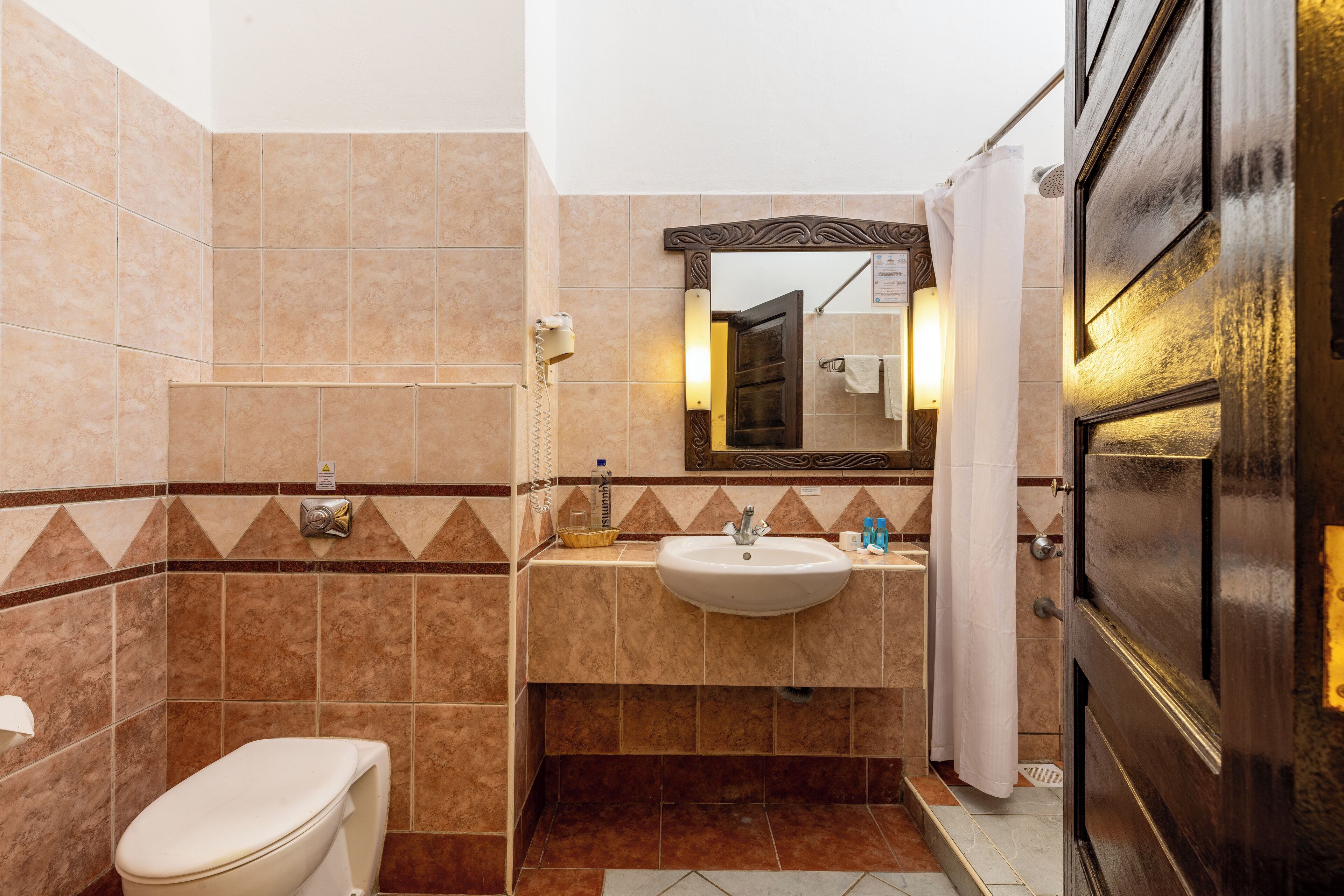 A bathroom with a toilet, sink, and mirror.