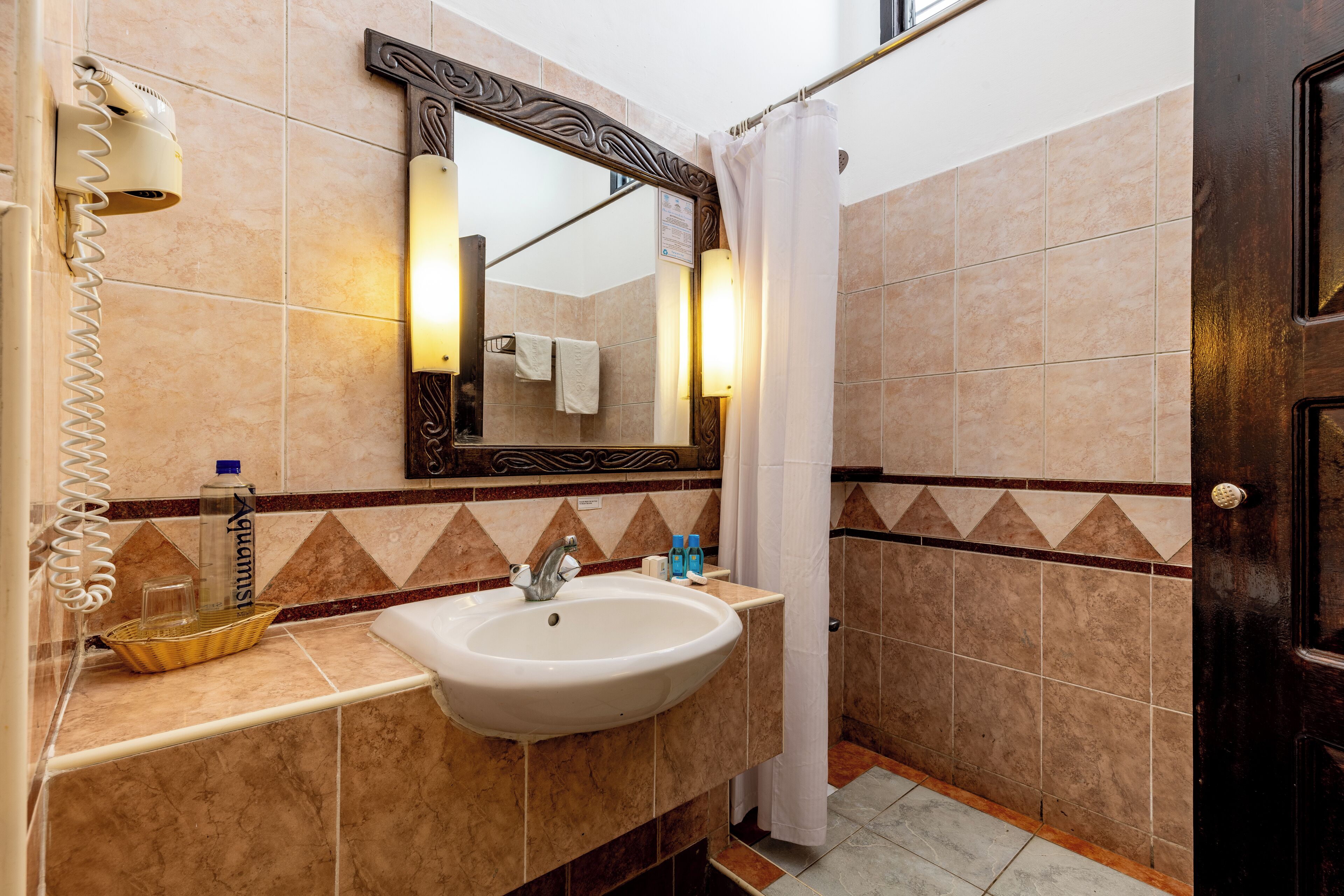 A bathroom with a white sink, a mirror, a towel rack, a shower curtain, and a door.
