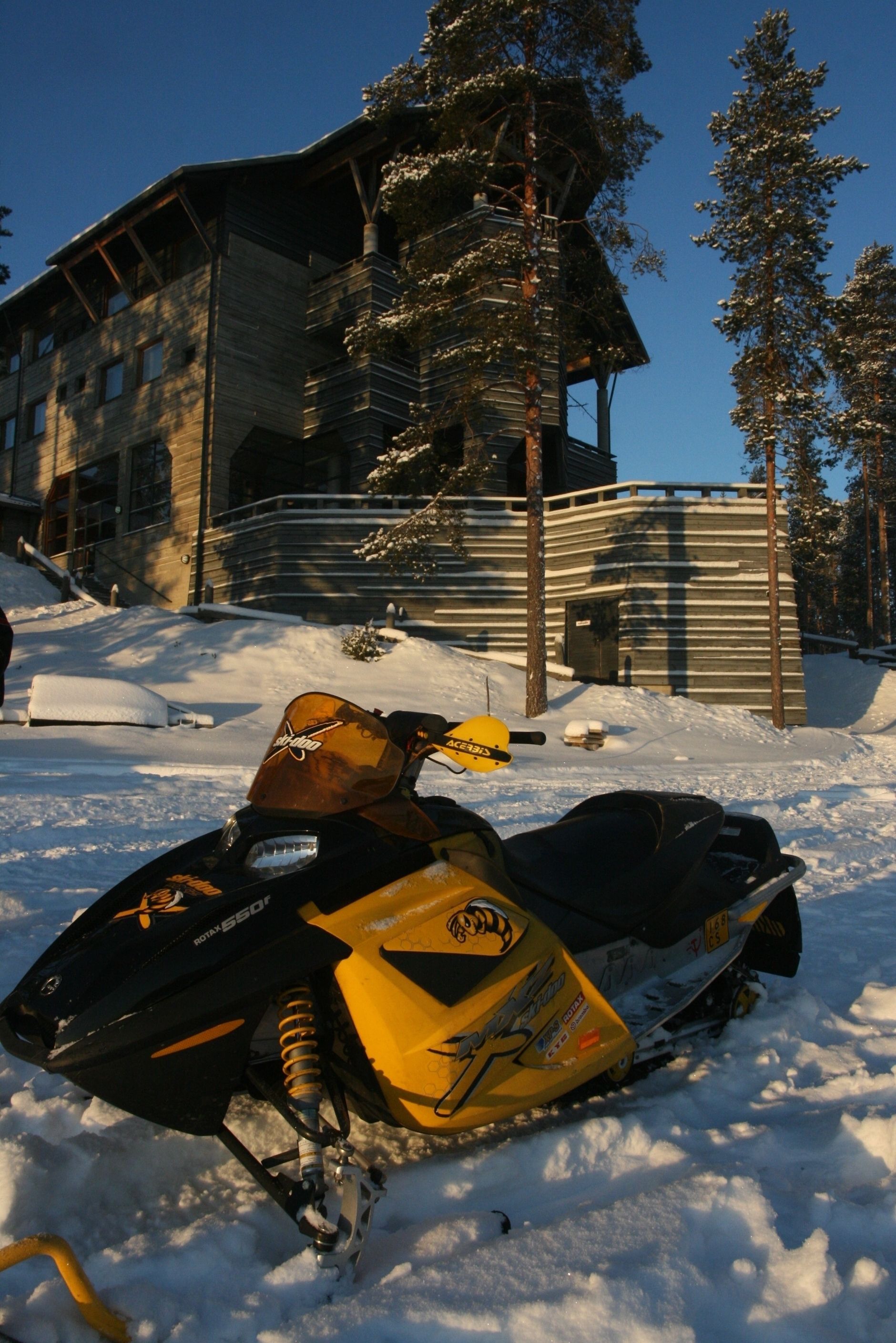 A snowmobile parked in front of a building with a sloped roof and wooden exterior.