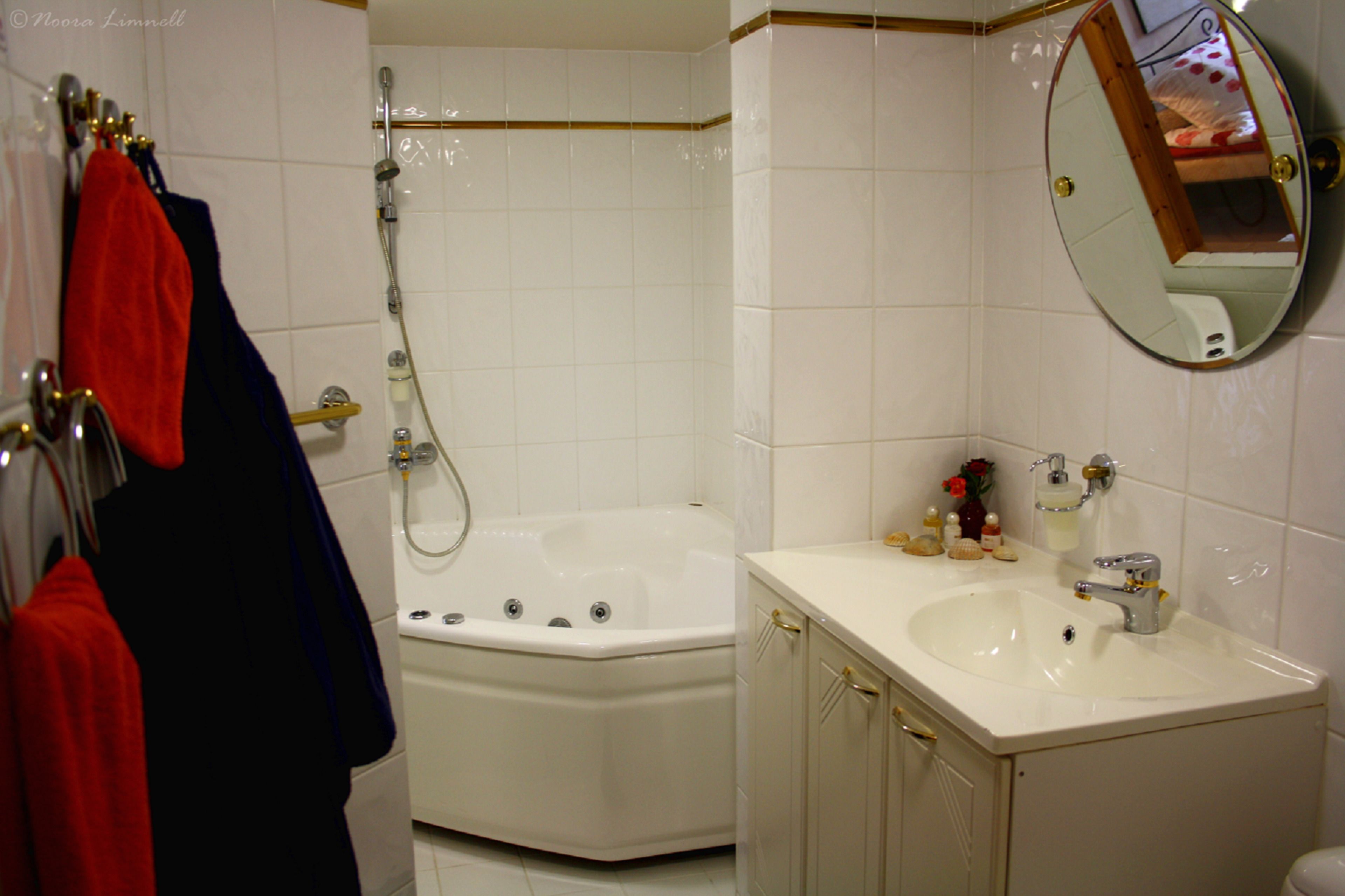 A bathroom with a white bathtub, a sink, and a mirror.