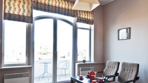A room with a herringbone wooden floor, a dining table with chairs, a sofa, a hanging lamp, and large windows with curtains. - Apartament Nadmorski Sopot 2 (Sopot)