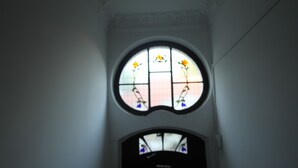 A narrow, dimly lit hallway with a stained glass window featuring floral designs. - Apartament Nadmorski Sopot 2 (Sopot)