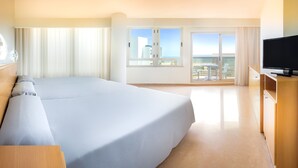A hotel room with a large bed, a TV, a balcony with a view of the city, and a table with chairs outside. - Hotel RH Gijón By Hoteles RH (Gandia)