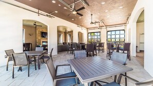 A spacious indoor dining area with multiple tables and chairs, high ceilings with exposed beams, and large windows allowing natural light.