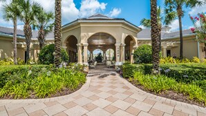 A covered walkway leading to a building with a tiled floor and palm trees.