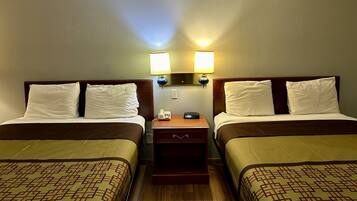 Une chambre d’hôtel avec deux lits, chacun doté d’une tête de lit, d’une table de chevet avec une lampe et d’un téléphone.