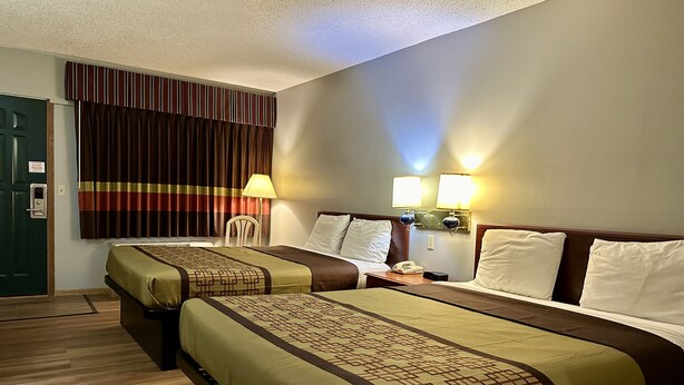 Ein Hotelzimmer mit zwei Betten, einem Schreibtisch, einem Stuhl, einer Lampe und einem Nachttisch.