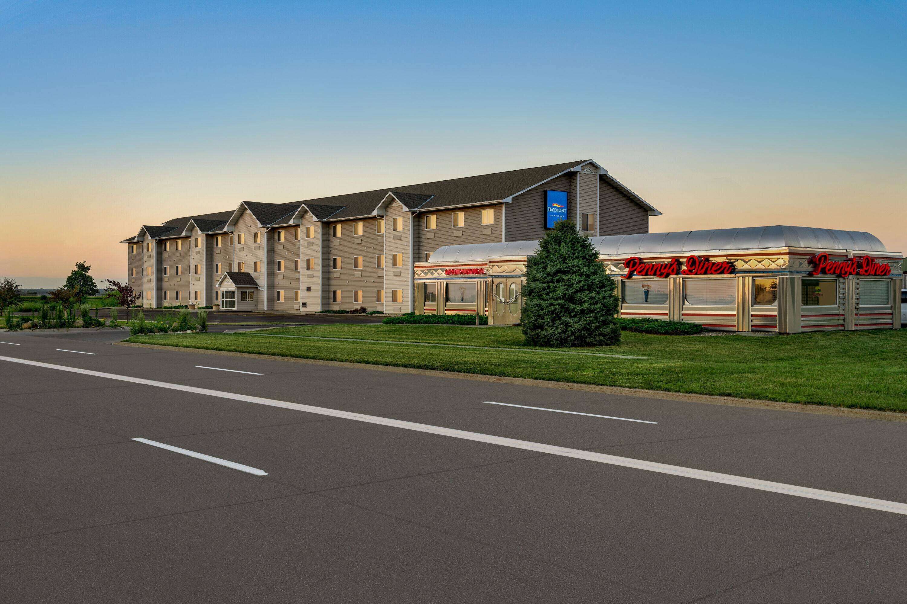 A hotel with a modern design, featuring a large building with multiple windows and a parking lot in front.