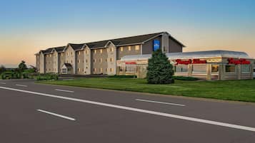 A hotel with a modern design, featuring a large building with multiple windows and a parking lot in front.