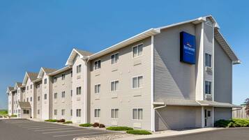 Un hotel de varios pisos con un llamativo letrero de Baymont, un estacionamiento y un exterior bien cuidado.