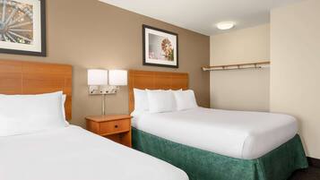 A hotel room with two beds, a nightstand with lamps, and framed pictures on the wall.