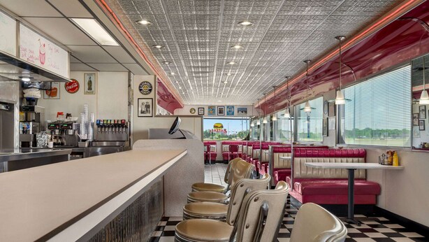 A diner interior with a counter, booths, and a checkered floor.