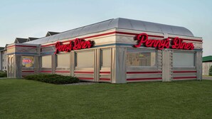 A diner with a classic design, featuring a prominent red neon sign and a 'OPEN' sign.