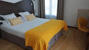 Una habitación de hotel con cama, una silla y una ventana con cortinas.