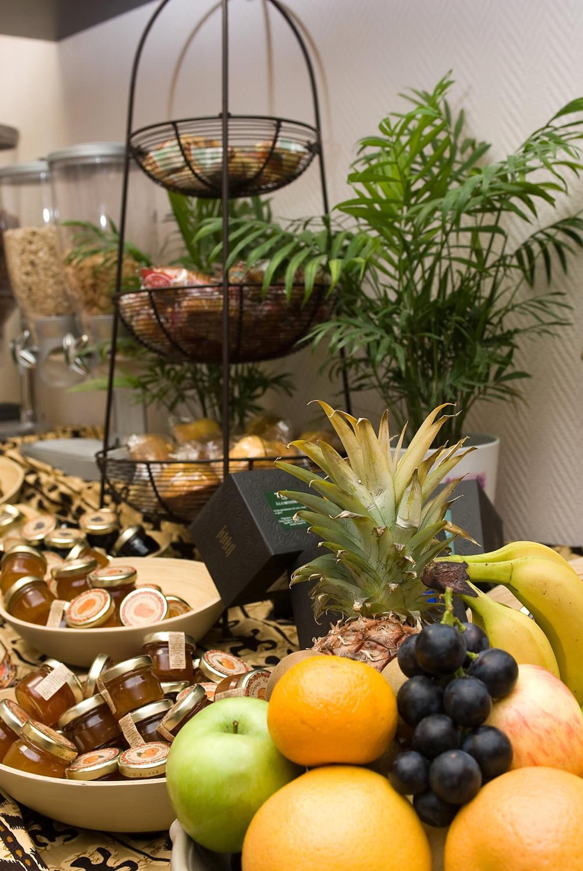 Une table avec différents fruits, un ananas et des pots de confitures.