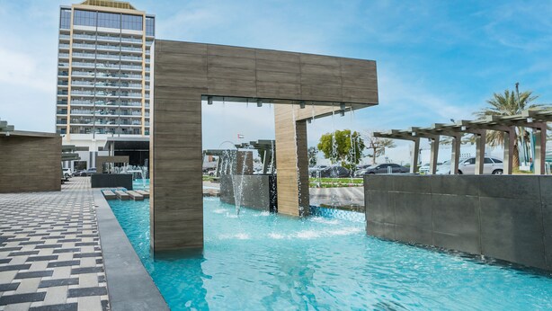 Een zwembad met een modern architectonisch ontwerp, inclusief een houten pergola en een fontein.