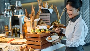 Een buffet met verschillende gerechten en een persoon die serveert.