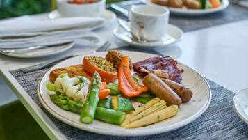 A breakfast plate with various foods including sausages, vegetables, and a piece of meat.
