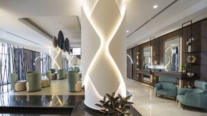 Een moderne lobby met een centraal lichtobject, zithoeken en een receptiebalie.