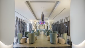 Een moderne lobby met een centrale zithoek, een flatscreen televisie en een bordje 'Tea Garden'.