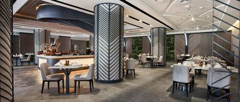 A modern restaurant with high ceilings, sleek columns, and contemporary furniture.