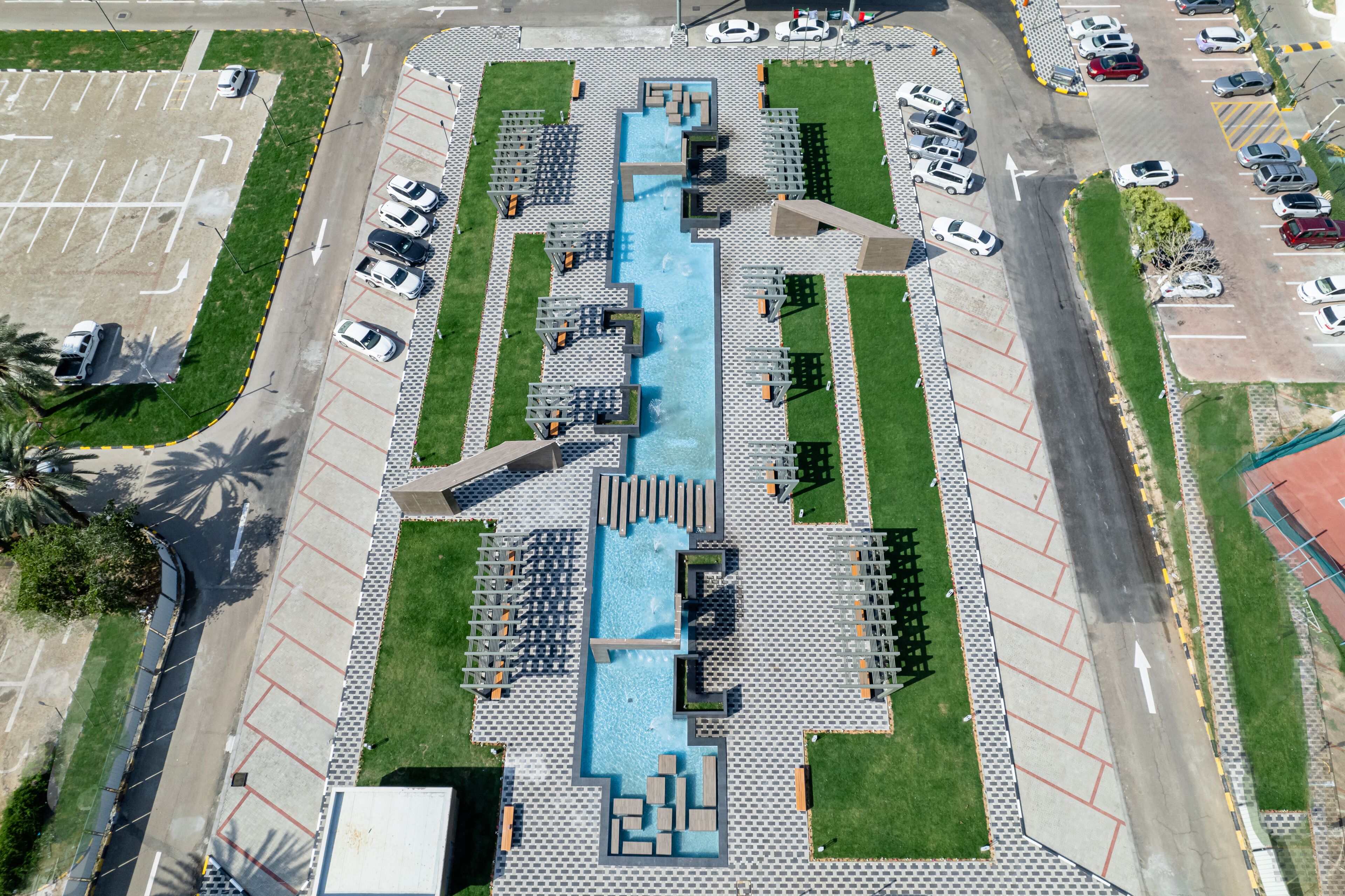Vista aérea de un estacionamiento con piscina central, rodeado de zonas de estar y áreas verdes.