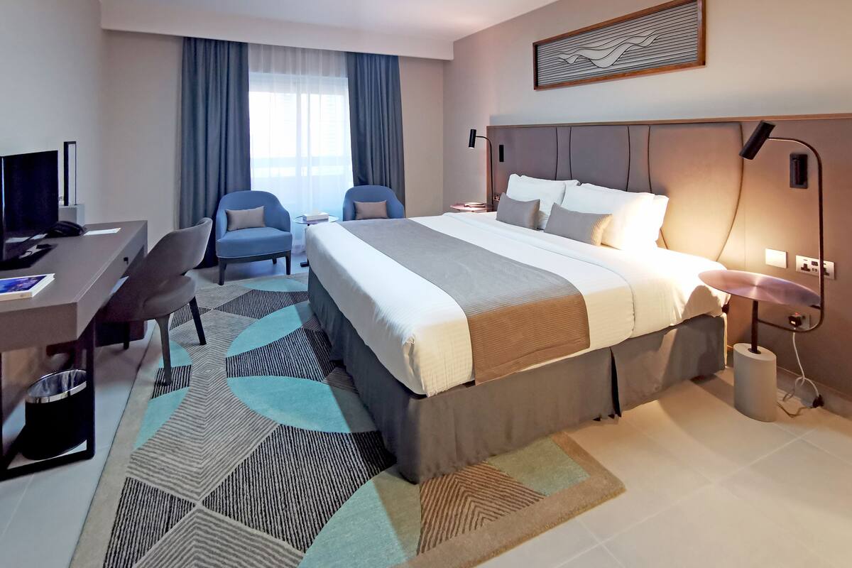 Ein Hotelzimmer mit Bett, Schreibtisch, Stühlen und Fernseher.