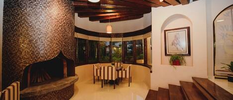 A spacious lobby with a mosaic wall, a wooden bench, a dining area with chairs, and a framed picture on the wall.