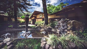 A traditional building with a clock, surrounded by a natural landscape including trees, a pond, and rocks. - Loto Azul Resort and Spa (Valle de Bravo)