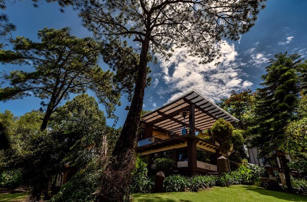 A traditional Japanese-style building with a wooden structure, surrounded by lush greenery and trees.