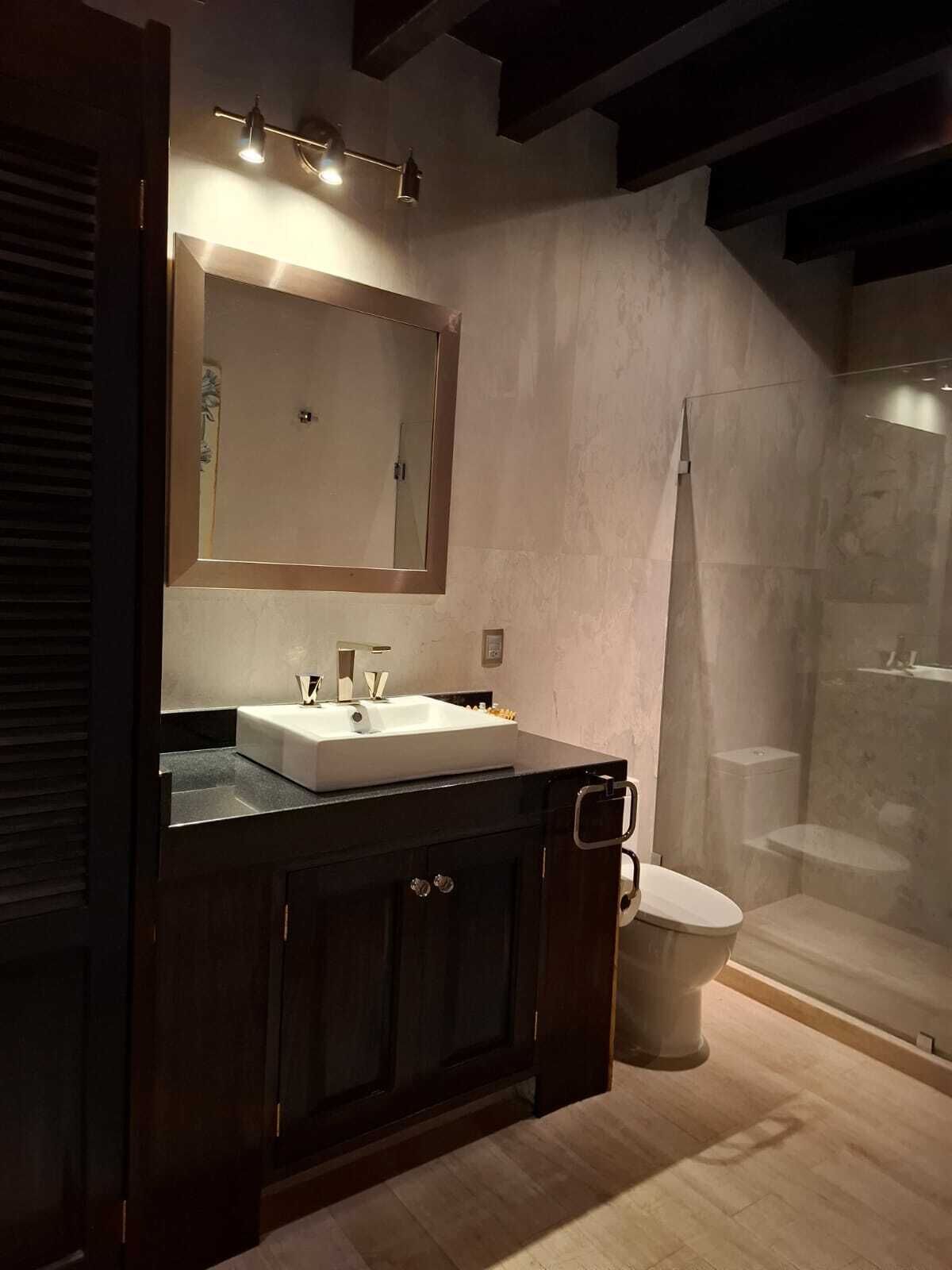 A modern bathroom with a large mirror, a sink, and a shower.