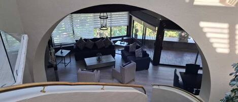 Un interior moderno con una escalera que conduce a una sala de estar con sofá, mesa de centro y mesa de comedor.
