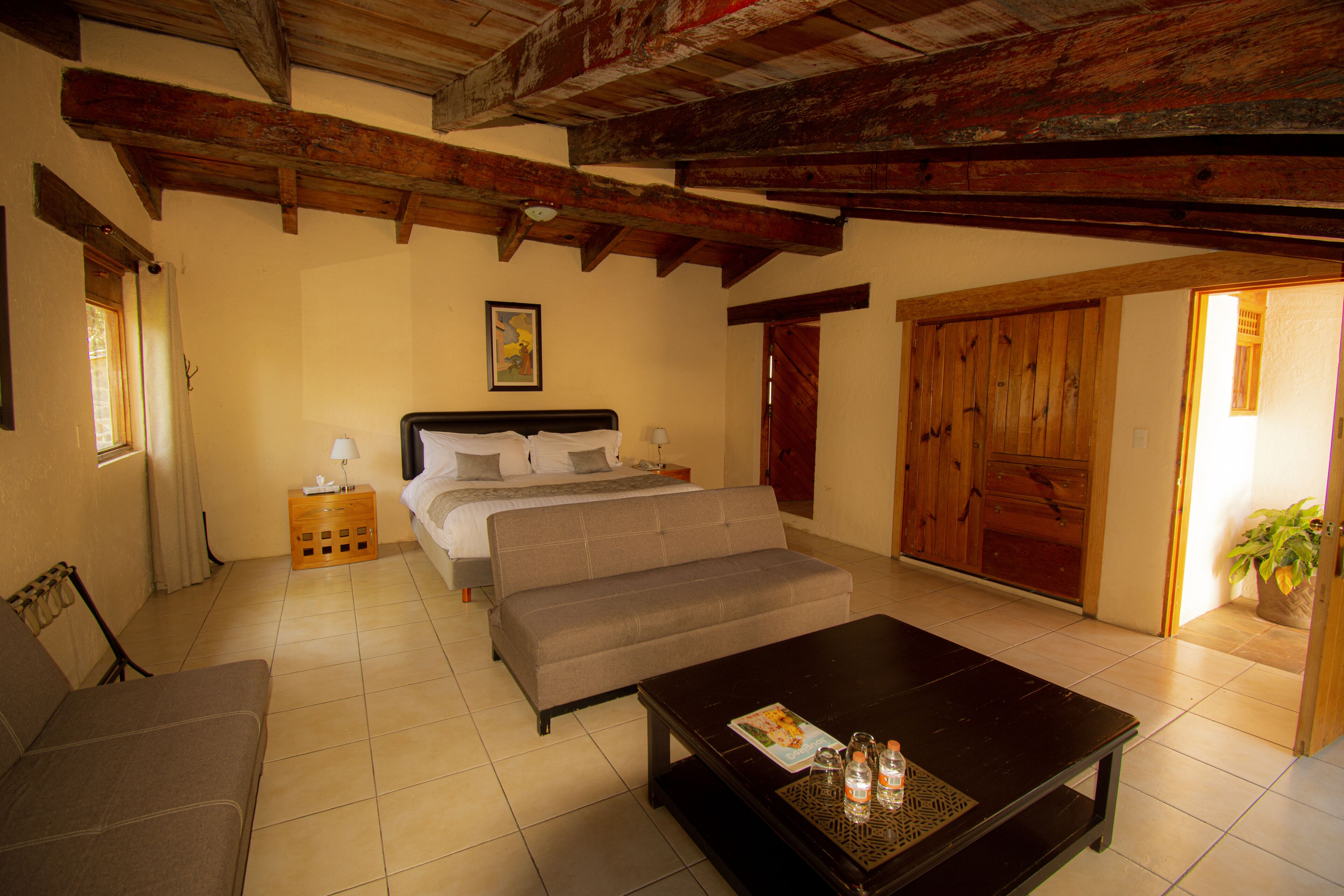 A bedroom with a bed, a sofa, a coffee table, and a wooden ceiling.