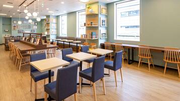 A library cafe with tables and chairs, bookshelves, and a large window.
