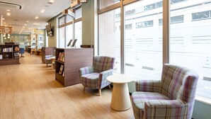 Un coin lecture confortable avec des fauteuils à carreaux, une petite table ronde et une bibliothèque.