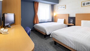 Une chambre d’hôtel avec deux lits, un bureau équipé d’un ordinateur et d’un téléphone, une télévision et une fenêtre avec des rideaux.