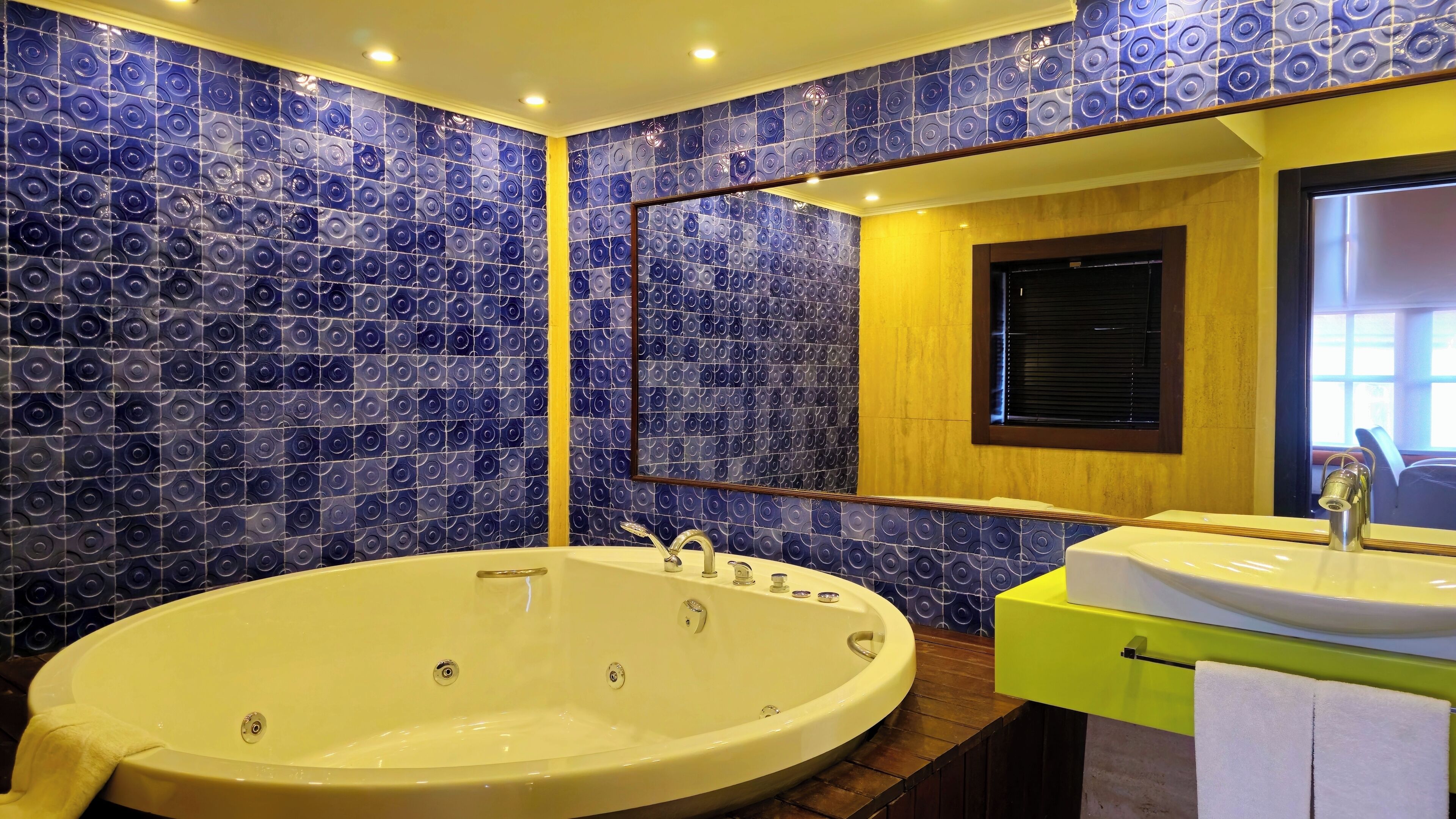 A bathroom with a large bathtub, a sink, and a mirror.