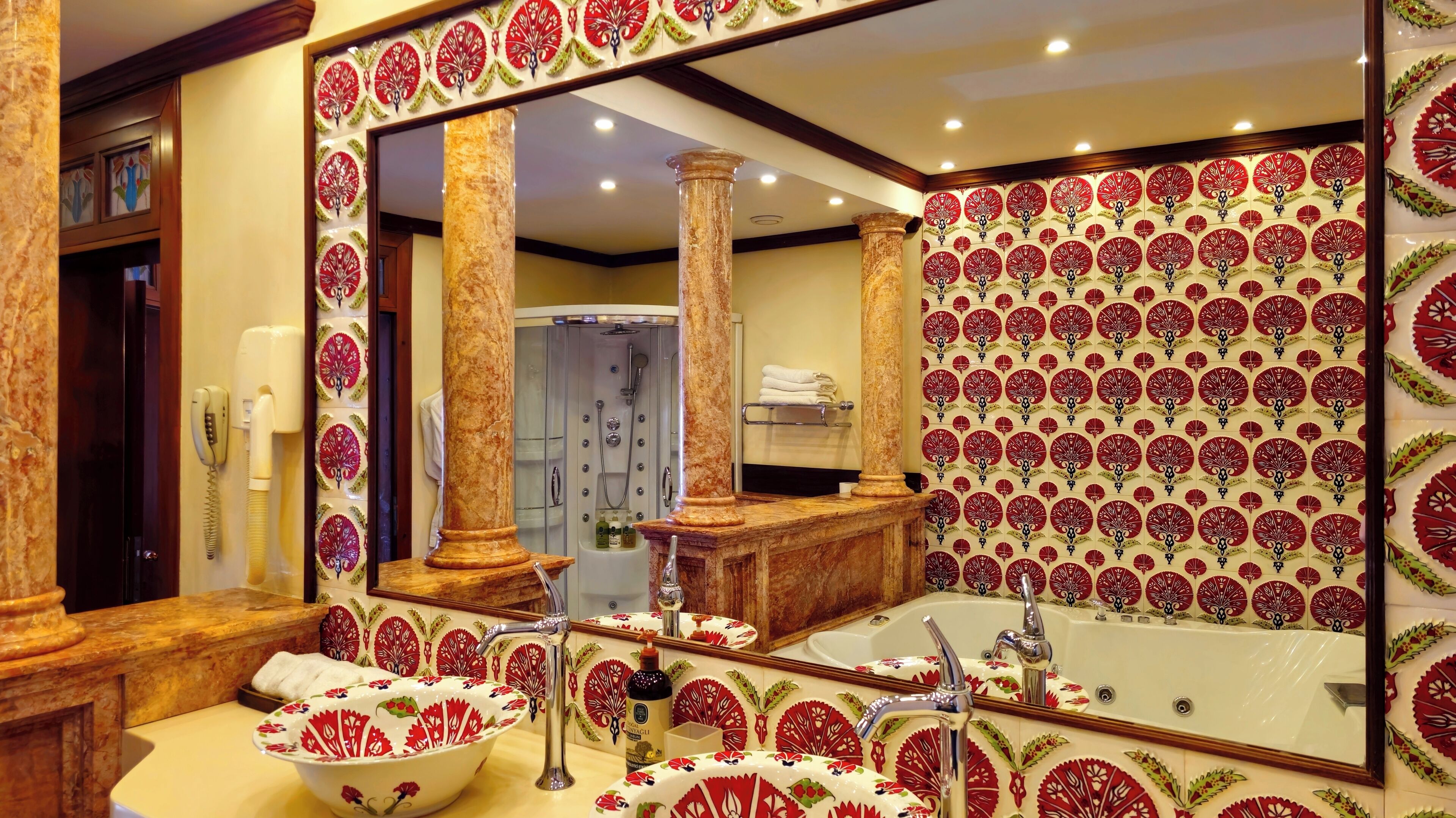 Un baño con un espejo grande, un lavamanos con un lavabo de estilo floral, una bañera y una zona de ducha.