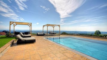 Una piscina techada, una piscina al aire libre, sombrillas