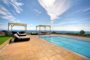 A swimming pool with two wooden gazebos, lounge chairs, and a stone patio. - Revita Hotel Kocher (Sankt Agatha)