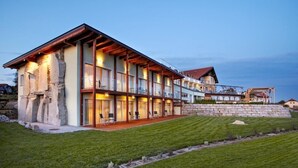 Una casa moderna de dos pisos con fachada de piedra, ventanas amplias y un césped cuidado.