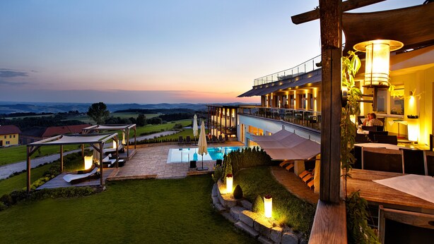 Un hotel con piscina, mobiliario exterior y vistas al campo.