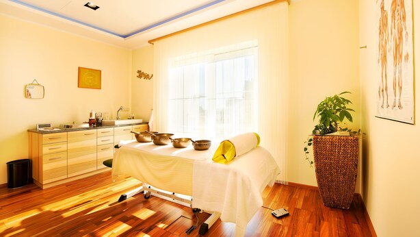 A room with a bed, a bedside table with bowls, a potted plant, and a window with curtains. - Revita Hotel Kocher (Sankt Agatha)