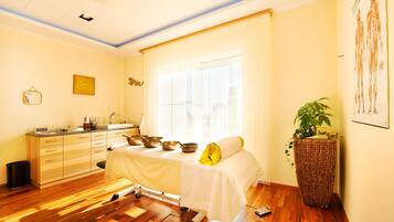 Relax in a serene space with a massage table, sink, and lush greenery.